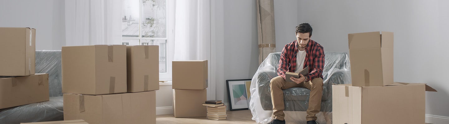 Renter sitting in empty room surrounded by boxes