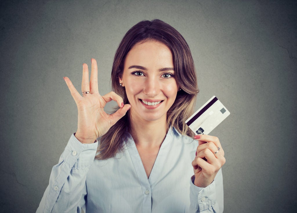 happy young business woman with credit card giving ok hand sign gesture
