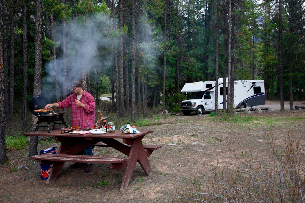 Man cooking at campground picnic table