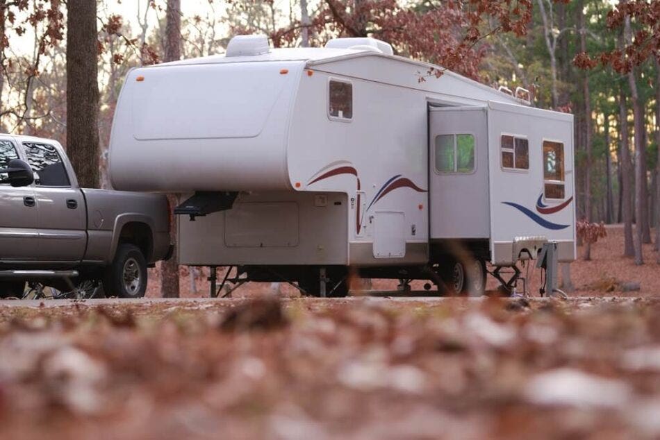 A newer fifth wheel parked in a campsite during autumn.