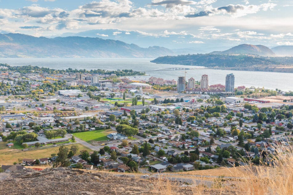 A view of downtown Kelowna from the top of Knox Mountain with Okanagan Lake, William R. Bennett bridge, and mountains in the distance.