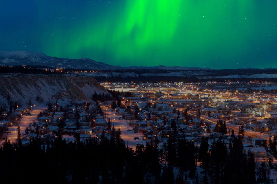 Green Aurora borealis northern lights in the night sky over downtown Whitehorse, capital of the Yukon Territory, Canada, in winter.