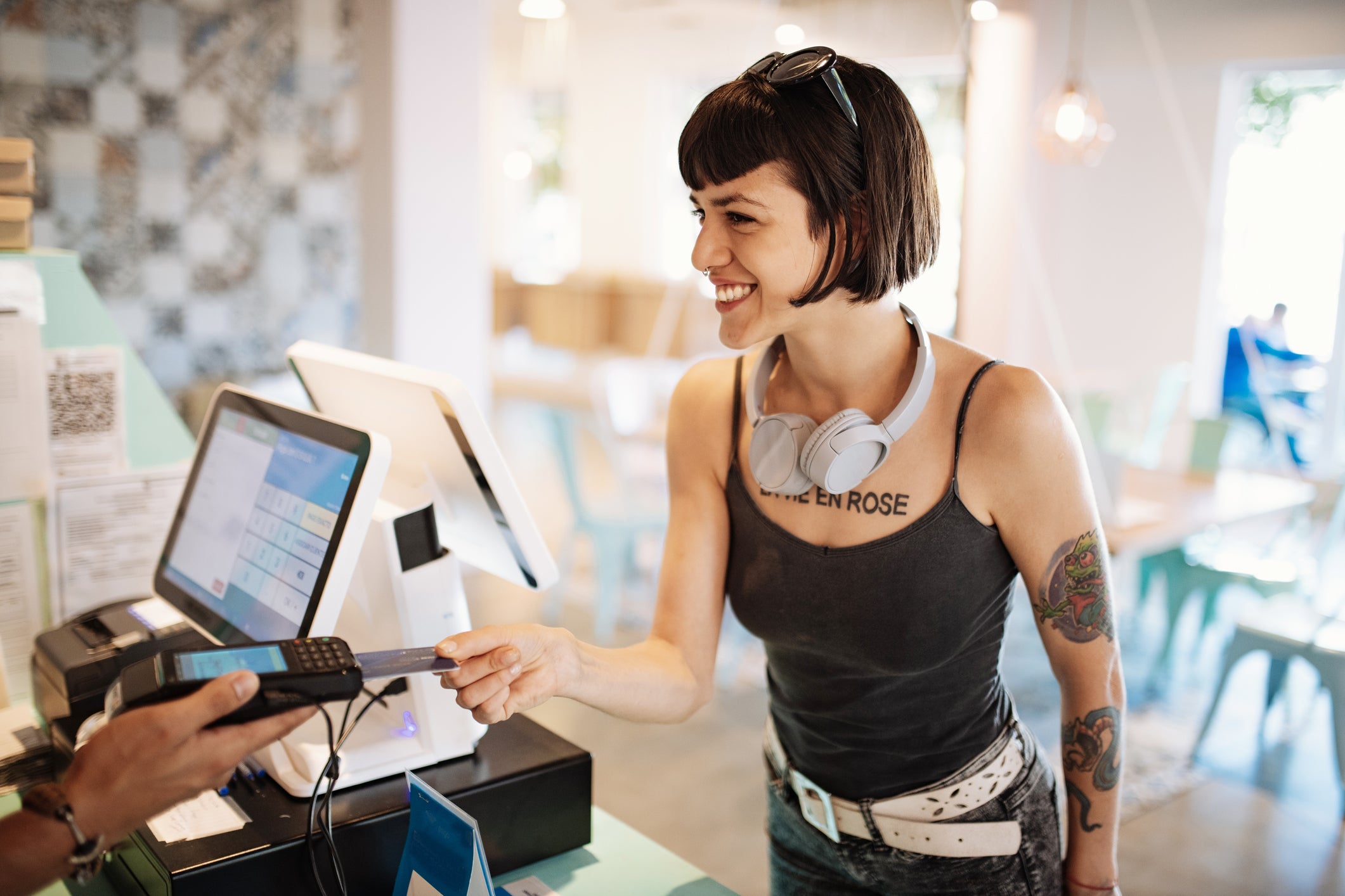 Latina woman paying with credit card in cafe, ordering take out food