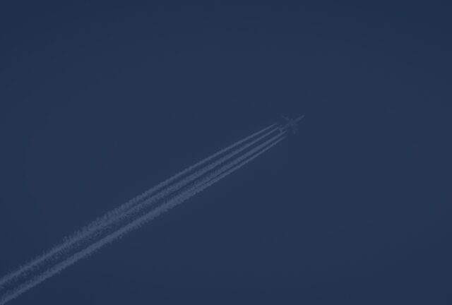 a jet in the sky with condensation trails behind, highlighting aviation insurance