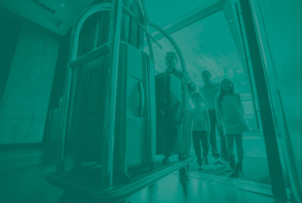 Luggage on a luggage cart in a hotel with family walking behind it