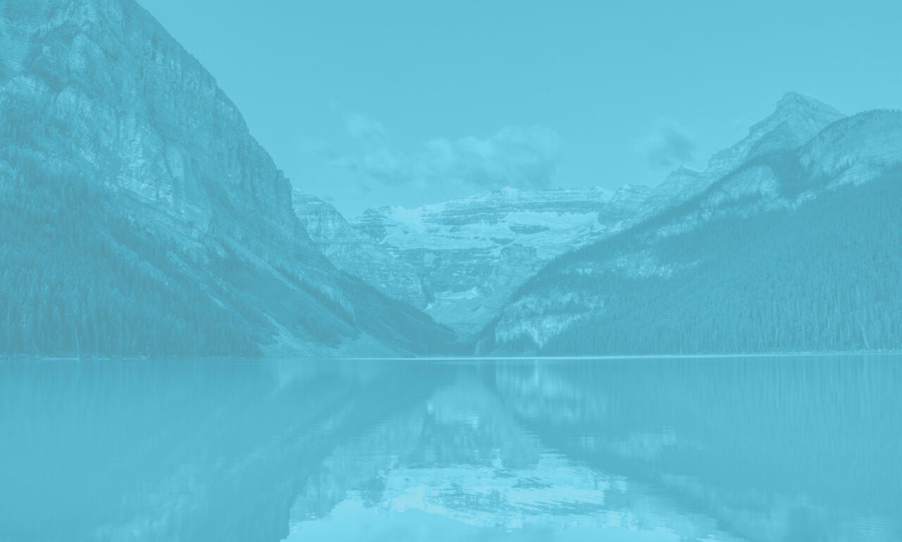 Pristine lake in Alberta with white capped mountains int he background