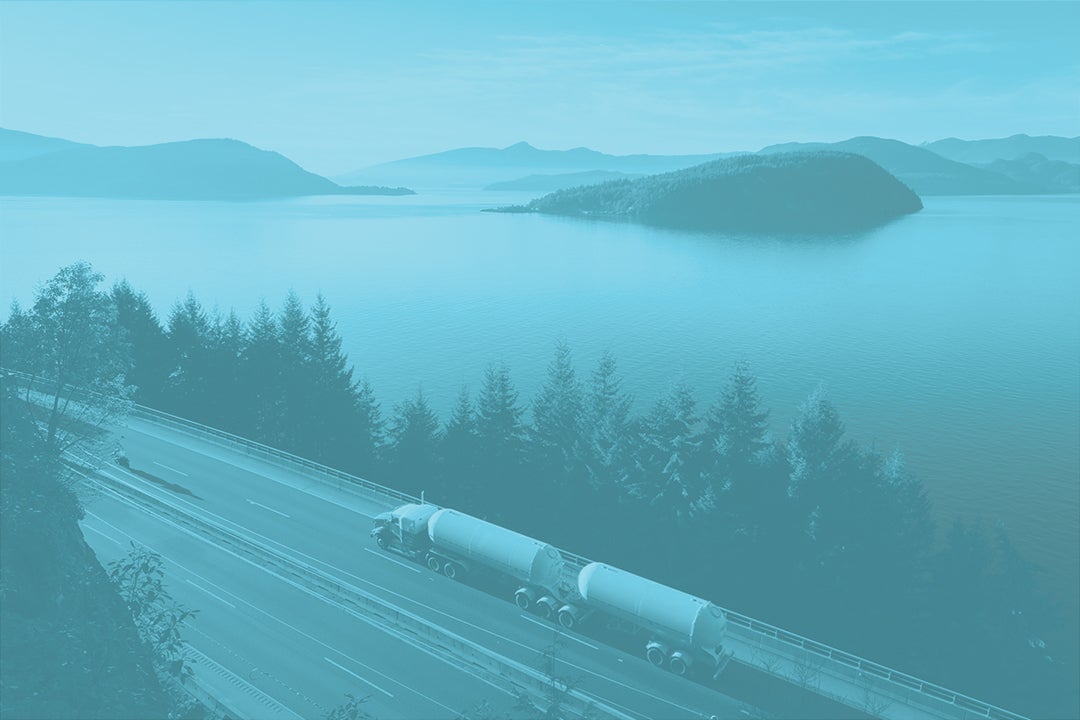 View of a commercial truck driving on a Canadian highway alongside the ocean