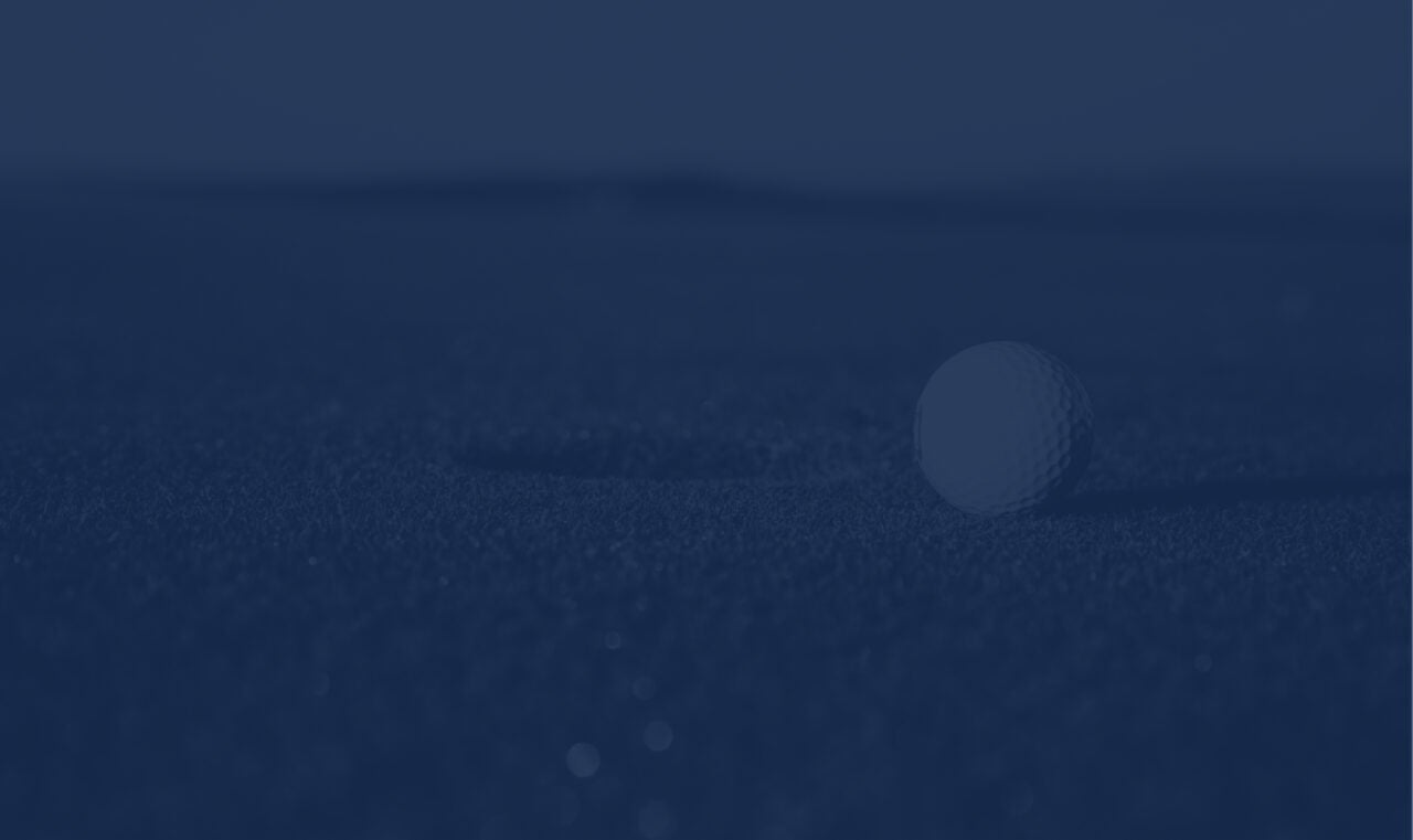 Golf ball on a green an inch away from the hole