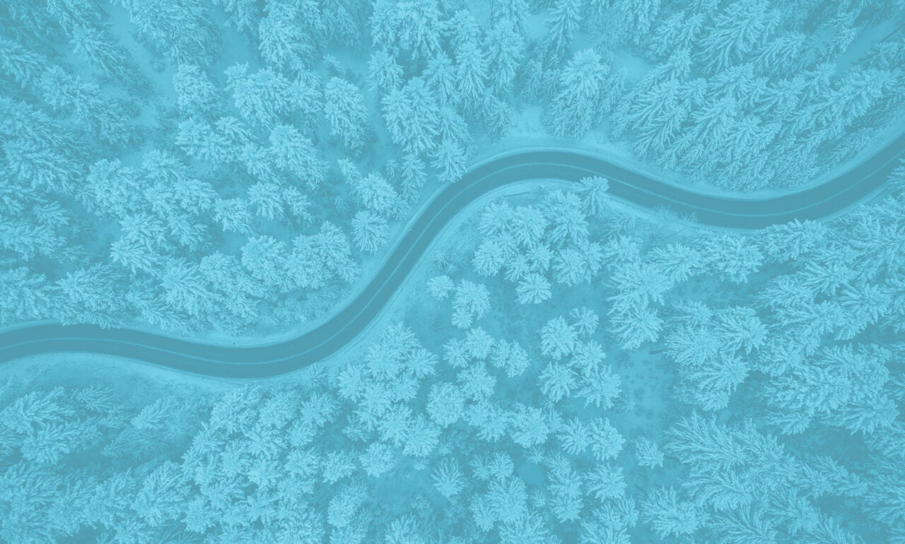 Aerial view of a winding road through a snowy forest