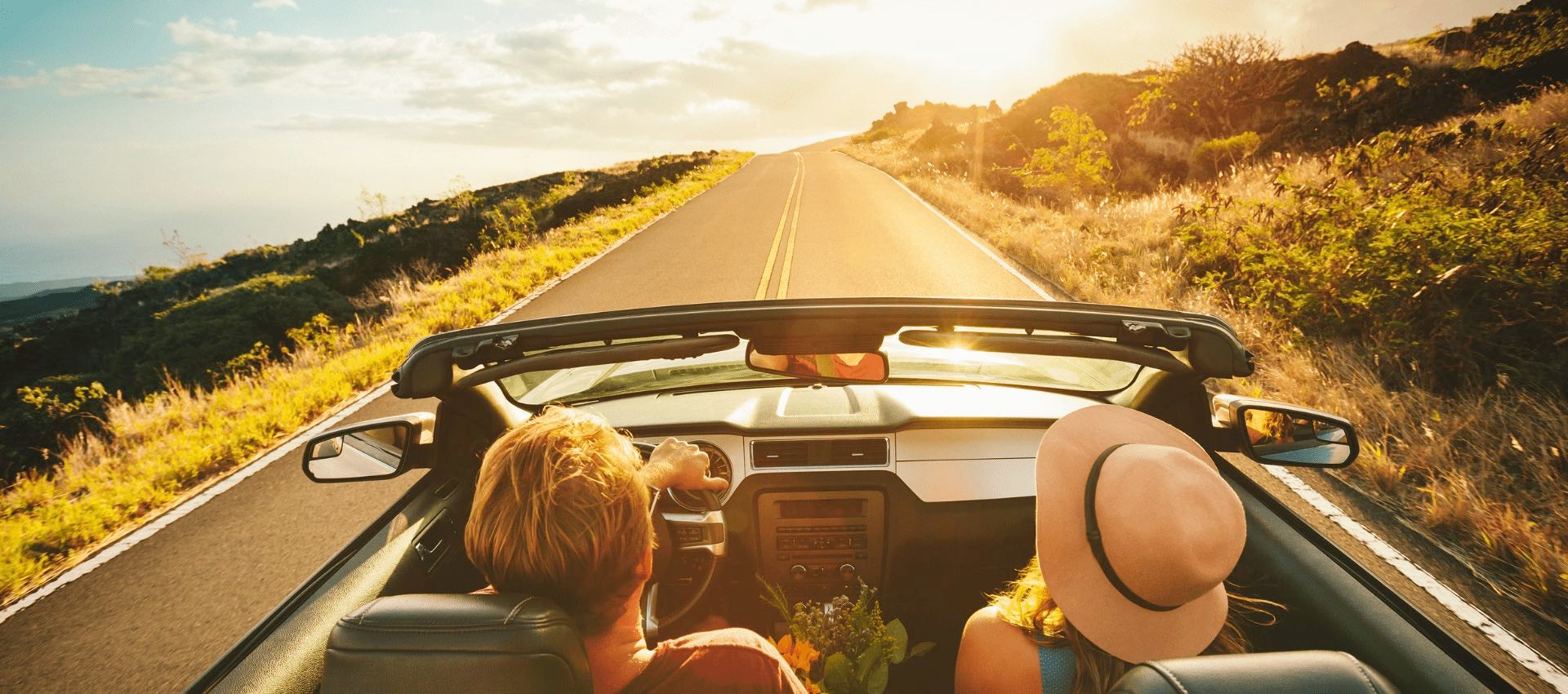 Top view of couple driving in convertible on back road