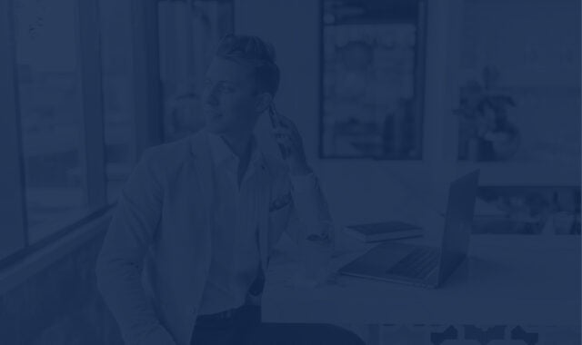 Man in suit sitting at a coffee bar while talking on his cellphone