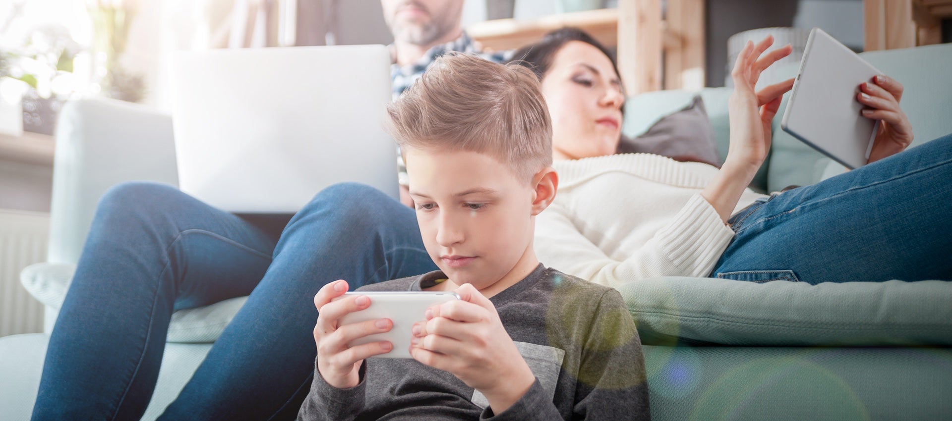 Family lounging on couch with all three looking at devices