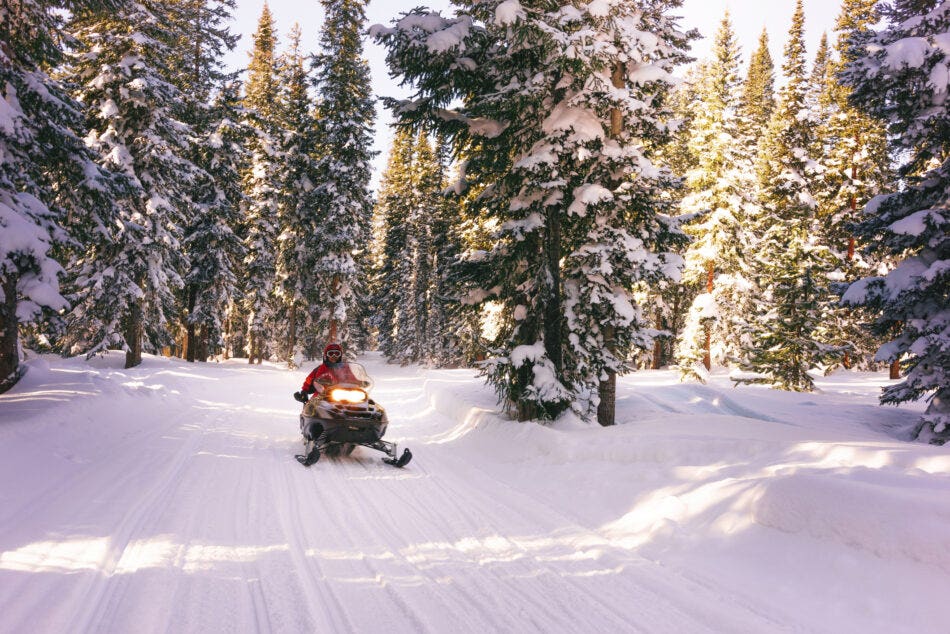 A snowmobiler safely operating during the day