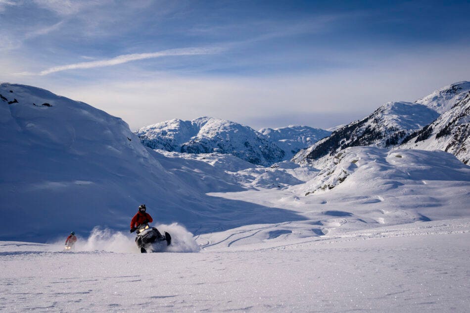 Backcountry snowmobiler rides across glacier through fresh powder snow, Whistler