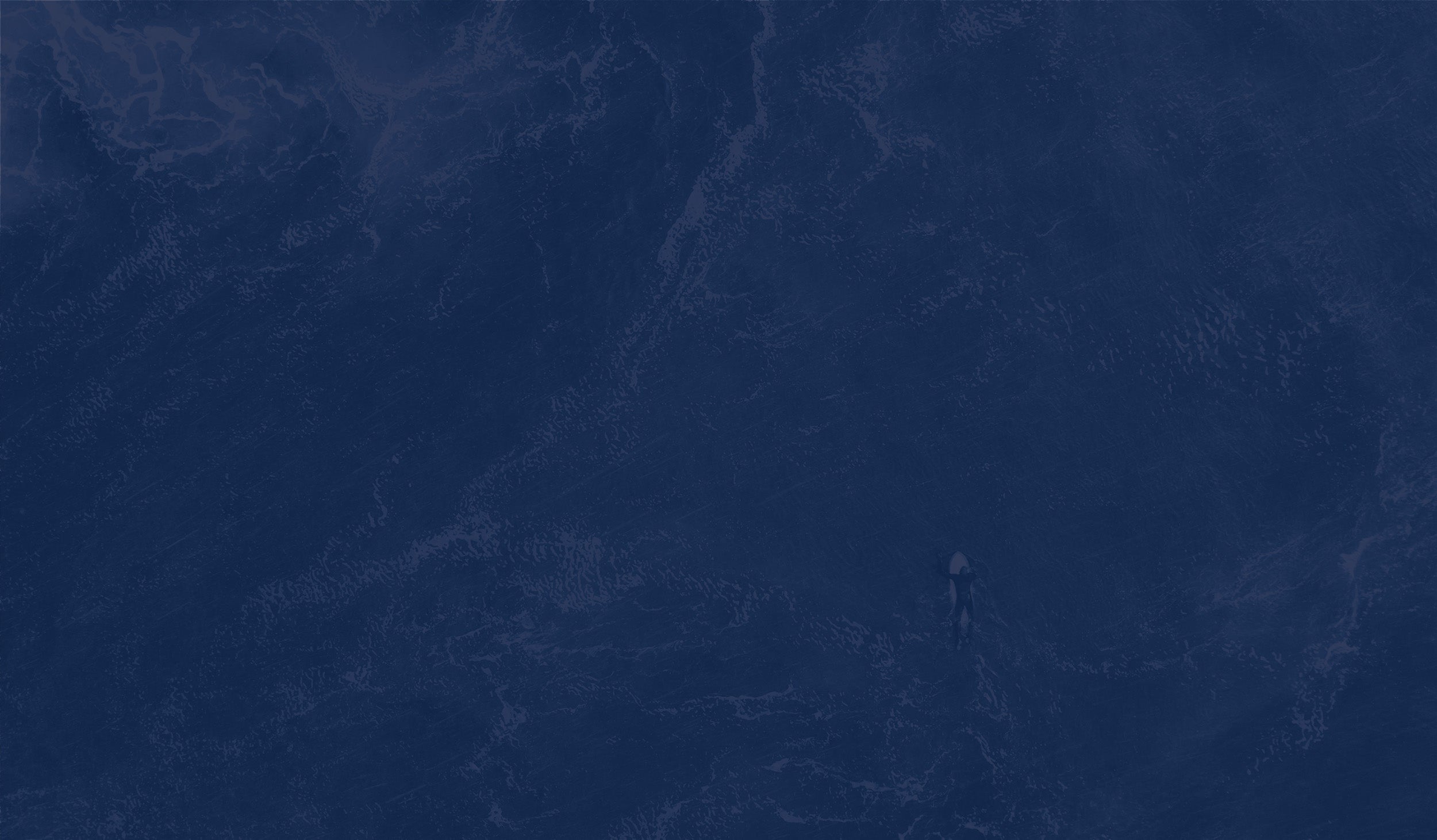 Overhead view of a surfer on their board paddling through the water